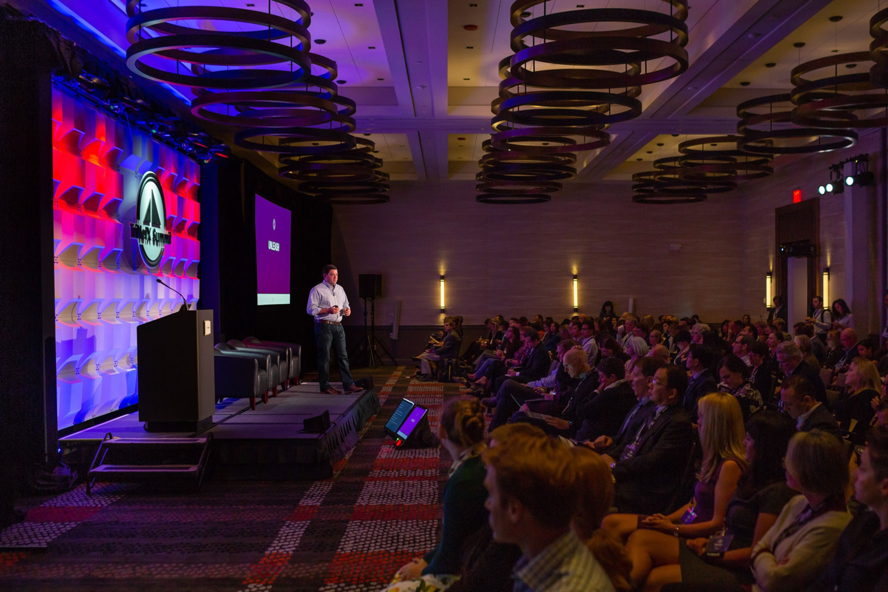 Photo of the TriNetX Summit event overlooking the speaker stage on the left and the audience seated on the right.